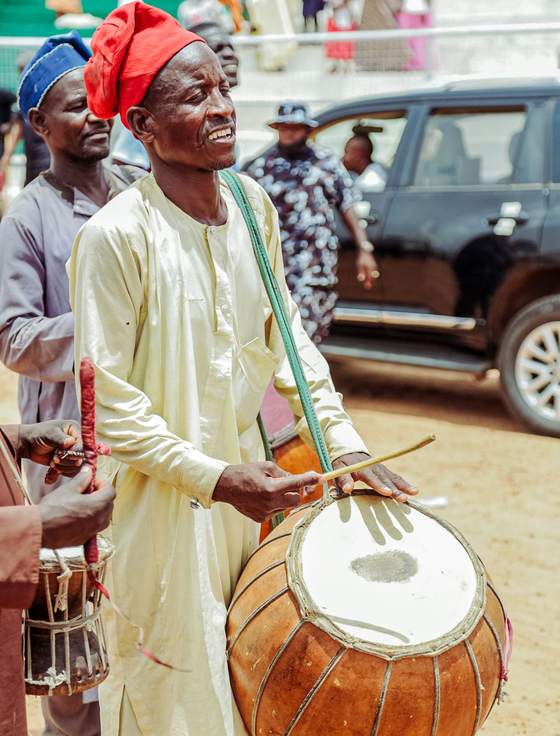 A drummer in traditional dress performing at a festival